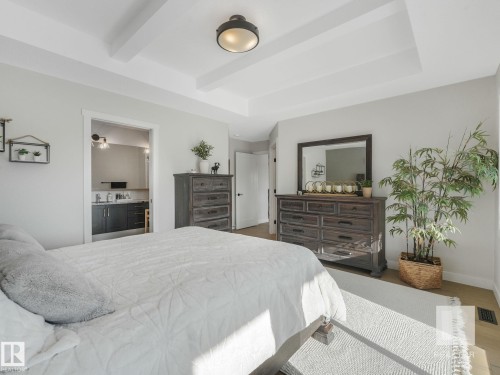 Bedroom featuring connected bathroom, a tray ceiling, beamed ceiling, and wood finished floors - 209 55101 Ste. Anne Trail, Rural Lac Ste. Anne County, AB - Indoor Photo Showing Bedroom