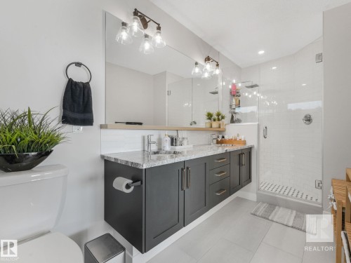 Full bath with double vanity, a stall shower, decorative backsplash, and light tile patterned flooring - 209 55101 Ste. Anne Trail, Rural Lac Ste. Anne County, AB - Indoor Photo Showing Bathroom