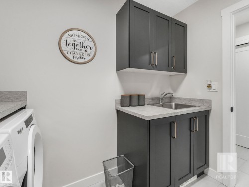 Laundry area with light tile patterned flooring and cabinet space - 209 55101 Ste. Anne Trail, Rural Lac Ste. Anne County, AB - Indoor Photo Showing Laundry Room
