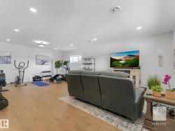 Living area with light wood-type flooring, a textured ceiling, and recessed lighting - 
