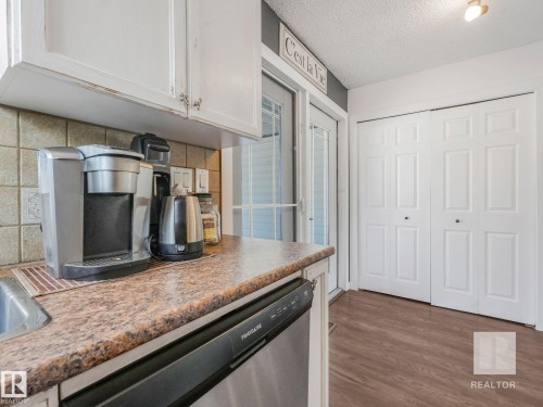 Kitchen with stainless steel dishwasher, tasteful backsplash, dark wood-type flooring, a textured ceiling, and white cabinets - 4504 48 Avenue, Onoway, AB - Indoor Photo Showing Kitchen