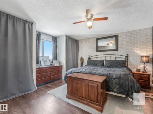 Bedroom featuring brick wall, hardwood / wood-style flooring, ceiling fan, a textured ceiling, and an accent wall - 4504 48 Avenue, Onoway, AB - Indoor Photo Showing Bedroom