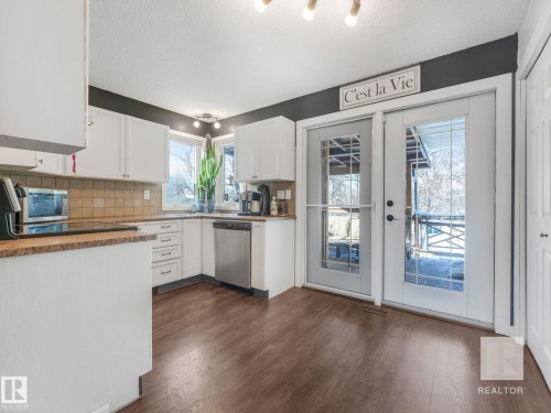 Kitchen with white cabinetry, decorative backsplash, dishwasher, dark wood-type flooring, and a textured ceiling - 4504 48 Avenue, Onoway, AB - Indoor Photo Showing Kitchen