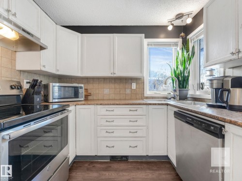 Kitchen featuring stainless steel appliances, white cabinetry, light countertops, a textured ceiling, and dark wood finished floors - 4504 48 Avenue, Onoway, AB - Indoor Photo Showing Kitchen
