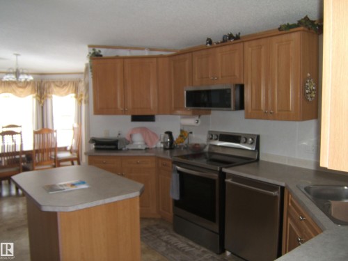 Kitchen with stainless steel appliances, a center island, suspended lighting, wood finish cabinetry, and light countertops - 125076 Twp Rd 540, Rural Two Hills County, AB - Indoor Photo Showing Kitchen
