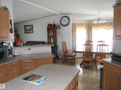Kitchen featuring hanging lights, light countertops, wood finish cabinetry, lofted ceiling with beams, and open floor plan - 125076 Twp Rd 540, Rural Two Hills County, AB - Indoor Photo Showing Kitchen