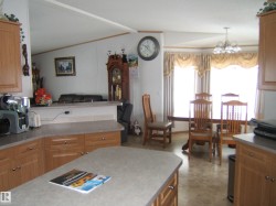 Kitchen featuring hanging lights, light countertops, wood finish cabinetry, lofted ceiling with beams, and open floor plan - 