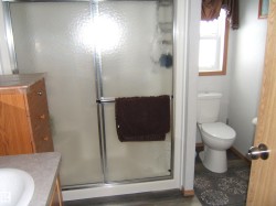 Full bath featuring vanity, a stall shower, and dark wood-style flooring - 