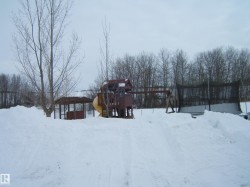 Yard covered in snow with a wooden deck, a playground, and a trampoline - 