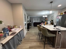 Kitchen featuring a kitchen breakfast bar, light wood-type flooring, pendant lighting, freestanding refrigerator, and light stone countertops - 
