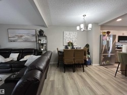 Dining area with light wood finished floors, a textured ceiling, and suspended lighting - 