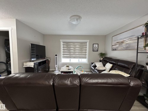 Living area with a textured ceiling and stacked washer / dryer - 120 1530 Tamarack Boulevard, Edmonton, AB - Indoor Photo Showing Living Room