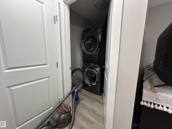 Laundry room with light wood finished floors and stacked washer / dryer - 