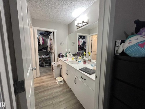 Bathroom featuring vanity, a textured ceiling, a walk in closet, and light wood-style floors - 120 1530 Tamarack Boulevard, Edmonton, AB - Indoor Photo Showing Bathroom