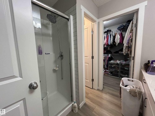 Bathroom featuring vanity, a shower stall, light wood-style floors, a walk in closet, and a textured ceiling - 120 1530 Tamarack Boulevard, Edmonton, AB - Indoor Photo Showing Bathroom