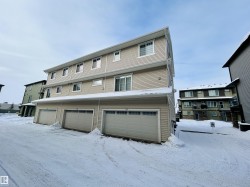Snow covered rear of property featuring a garage - 
