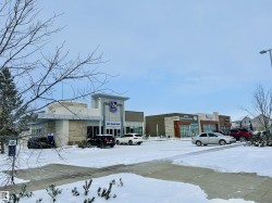 Snow covered building with view of commercial area and uncovered parking - 