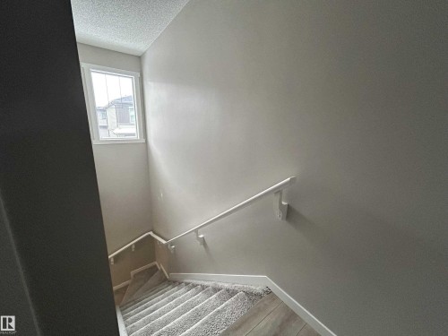 Staircase featuring a textured ceiling and baseboards - 120 1530 Tamarack Boulevard, Edmonton, AB - Indoor