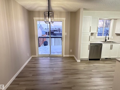 Unfurnished dining area with a textured ceiling, dark wood-type flooring, healthy amount of natural light, and suspended lighting - 4919 49 Avenue, Vimy, AB - Indoor