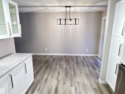 Unfurnished dining area with a textured ceiling, light wood-style floors, and a chandelier - 4919 49 Avenue, Vimy, AB - Indoor