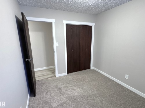 Unfurnished bedroom featuring light colored carpet, a textured ceiling, and a closet - 4919 49 Avenue, Vimy, AB - Indoor