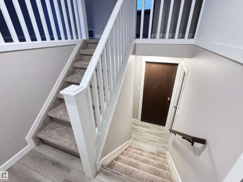 Stairway with baseboards and wood finished floors - 4919 49 Avenue, Vimy, AB - Indoor Photo Showing Other Room