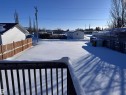 Yard layered in snow featuring a storage unit, a fenced backyard, and a residential view - 4919 49 Avenue, Vimy, AB  - Outdoor 