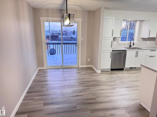 Unfurnished dining area featuring a textured ceiling, light wood-style floors, and suspended lighting - 4919 49 Avenue, Vimy, AB - Indoor Photo Showing Kitchen