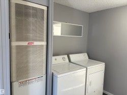 Laundry room featuring a heating unit, a textured ceiling, and washing machine and dryer - 