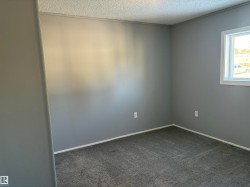 Unfurnished room with dark colored carpet and a textured ceiling - 