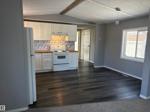 Kitchen with white cabinets, white appliances, tasteful backsplash, hanging light fixtures, and wood counters - 8 Evergreen Park Drive, Edmonton, AB - Indoor Photo Showing Kitchen