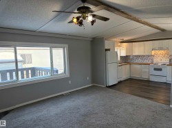 Kitchen featuring white appliances, white cabinetry, backsplash, a textured ceiling, and dark carpet - 