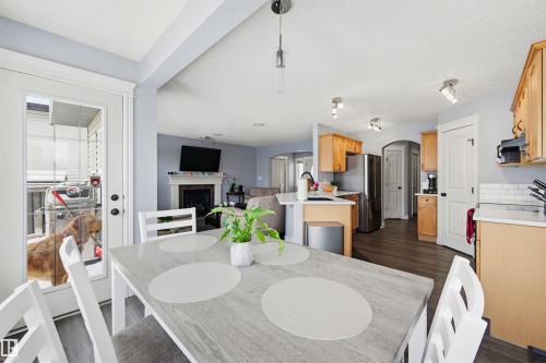 Dining room with arched walkways, a fireplace, and dark wood-style flooring - 4020 157A Avenue, Edmonton, AB - Indoor Photo Showing Dining Room