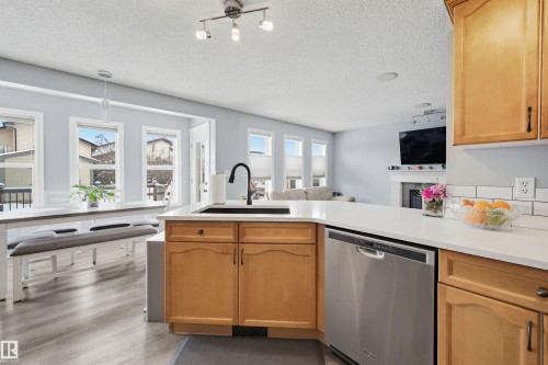 Kitchen with dishwasher, open floor plan, a peninsula, a fireplace, and a textured ceiling - 4020 157A Avenue, Edmonton, AB - Indoor Photo Showing Kitchen