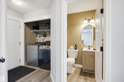Bathroom featuring vanity, a textured ceiling, light wood-style flooring, and washing machine and clothes dryer - 4020 157A Avenue, Edmonton, AB - Indoor Photo Showing Laundry Room
