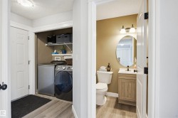 Bathroom featuring vanity, a textured ceiling, light wood-style flooring, and washing machine and clothes dryer - 