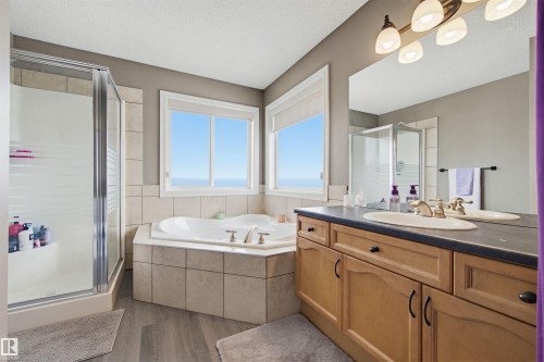 Bathroom with vanity, a shower stall, dark wood-type flooring, a textured ceiling, and a garden tub - 4020 157A Avenue, Edmonton, AB - Indoor Photo Showing Bathroom