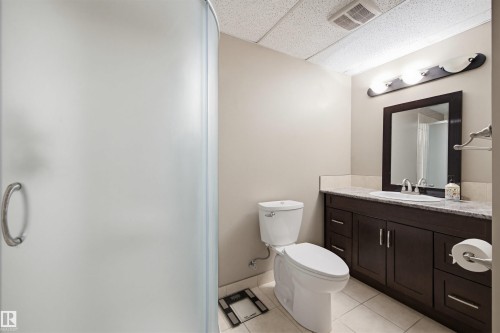 Full bath featuring a drop ceiling, vanity, light tile patterned floors, and a shower with shower door - 4020 157A Avenue, Edmonton, AB - Indoor Photo Showing Bathroom