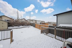 Yard layered in snow with a fenced backyard, a residential view, a wooden deck, and a storage shed - 