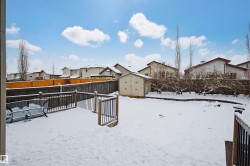 Snowy yard with a residential view, a storage shed, a fenced backyard, and a wooden deck - 