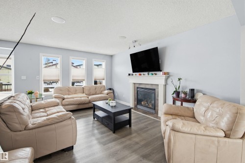 Living area with wood finished floors, a fireplace, a textured ceiling, and track lighting - 4020 157A Avenue, Edmonton, AB - Indoor Photo Showing Living Room With Fireplace