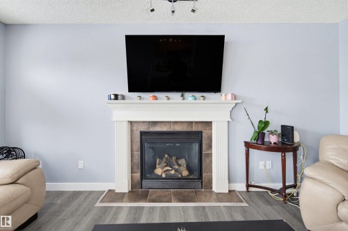 Detailed view of a textured ceiling, wood finished floors, and a tiled fireplace - 4020 157A Avenue, Edmonton, AB - Indoor Photo Showing Living Room With Fireplace