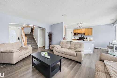 Living area with light wood-type flooring, arched walkways, and a textured ceiling - 4020 157A Avenue, Edmonton, AB - Indoor Photo Showing Living Room
