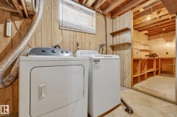 Laundry area with unfinished concrete floors, wood walls, and washer and clothes dryer - 