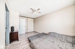 Bedroom featuring light wood finished floors, a closet, a textured ceiling, and a ceiling fan - 