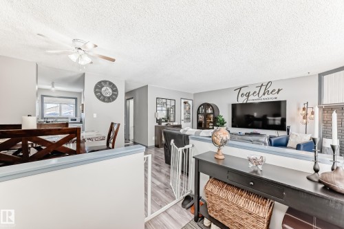 Living area with a ceiling fan, a textured ceiling, and light wood-style flooring - 214A Warwick Road, Edmonton, AB - Indoor Photo Showing Living Room