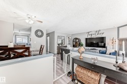 Living area with a ceiling fan, a textured ceiling, and light wood-style flooring - 