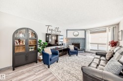 Living area featuring a brick fireplace, light wood-type flooring, and a textured ceiling - 