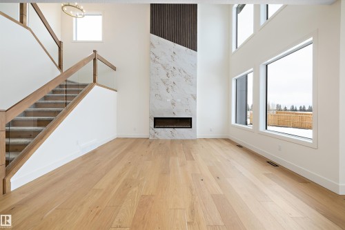 Unfurnished living room with a high ceiling, a high end fireplace, and light wood-style floors - 6871 Knox Loop Sw, Edmonton, AB - Indoor Photo Showing Other Room