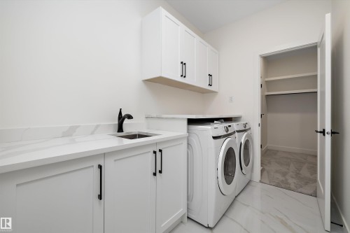 Laundry area featuring cabinet space, separate washer and dryer, and light marble finish floors - 6871 Knox Loop Sw, Edmonton, AB - Indoor Photo Showing Laundry Room